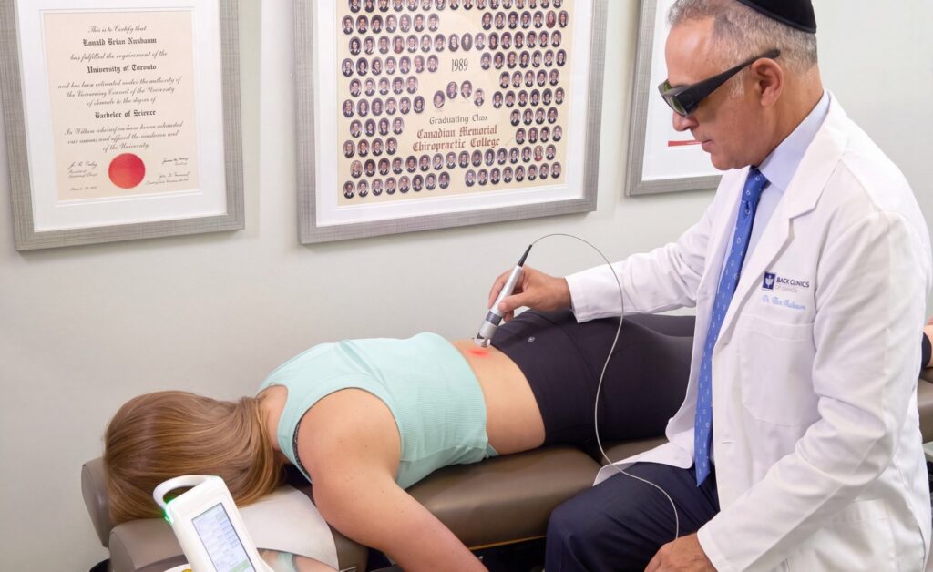 Dr. Ron Nusbaum applying Class IV laser therapy to a patient lying face down